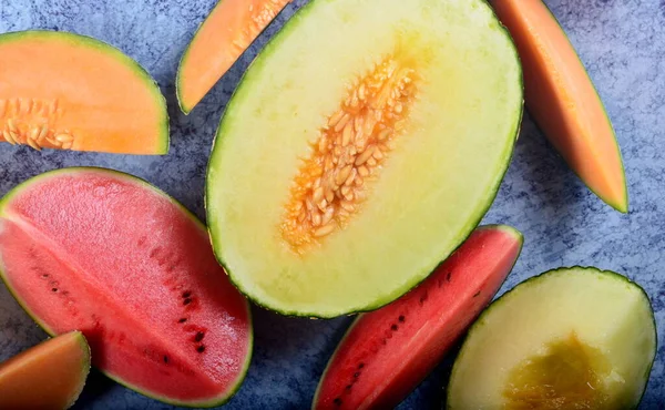 Leckere Bio Melonen Und Wassermelonen Halbiert Auf Blauem Steinhintergrund — Stockfoto
