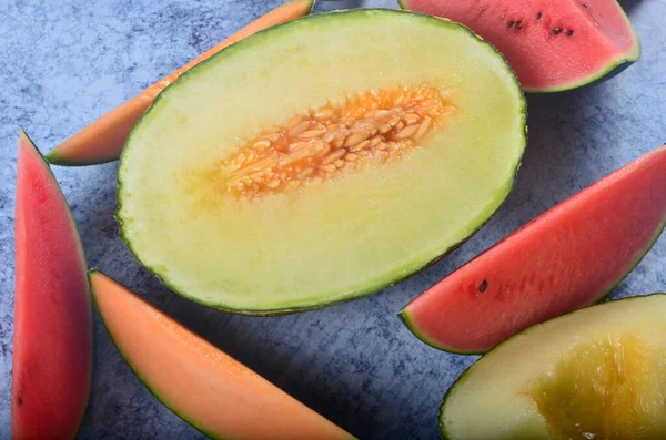 Lezzetli organik kavunlar ve karpuz mavi taş arka planda ikiye bölünmüş.