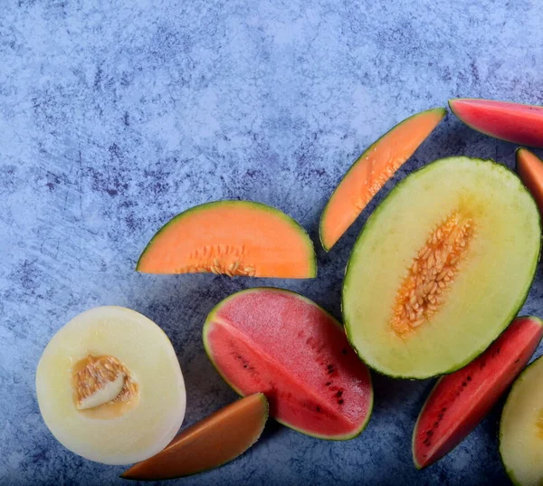 Taze kesilmiş kavunlar ve mavi taştan bir arka planda karpuz. Boşluk ve metin alanını kopyala