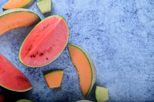 Taze kesilmiş kavunlar ve mavi taştan bir arka planda karpuz. Boşluk ve metin alanını kopyala