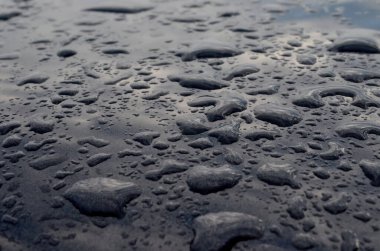 Koyu renk arabanın çatısına yağmur yağıyor. Yağmur yağdıktan sonra su damlıyor, seçici odaklanma.