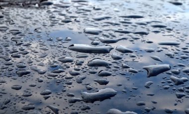 Koyu renk arabanın çatısına yağmur yağıyor. Yağmur yağdıktan sonra su damlıyor, seçici odaklanma.