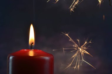 Koyu bir arka planda yanan bir mum ve sarı kıvılcımlar. Noel ve Yeni Yıl illüstrasyonu