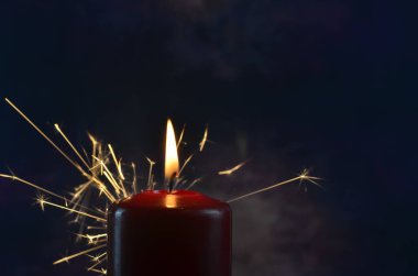 Koyu bir arka planda yanan bir mum ve sarı kıvılcımlar. Noel ve Yeni Yıl illüstrasyonu