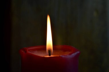 Yanan tek bir kırmızı mum ve dans eden alevler.