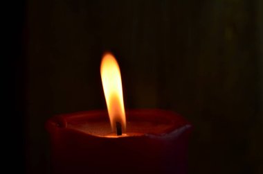 Yanan tek bir kırmızı mum ve dans eden alevler.