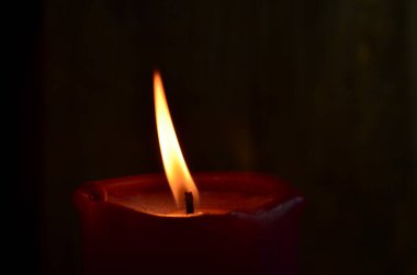 Yanan tek bir kırmızı mum ve dans eden alevler.