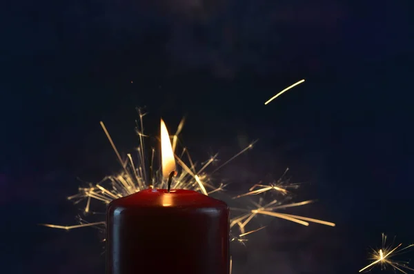 A burning candle and yellow sparks on a dark background. Christmas and New Year illustration