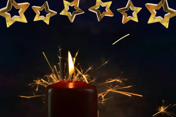 A burning candle and yellow sparks on a dark background. Christmas and New Year illustration