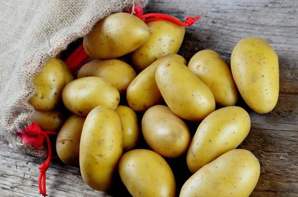 Çiğ patates yemeği. Tahta arka planda eski bir çantada taze patates. Yukarıdan görüntüle