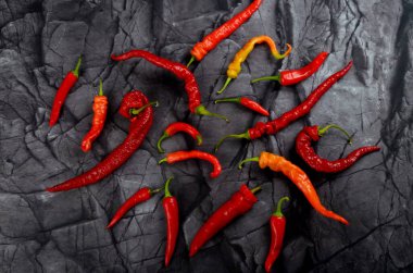 Doğal siyah taş arka planda bir sürü kırmızı kırmızı kırmızı biber, üst manzara.