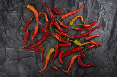 Doğal siyah taş arka planda bir sürü kırmızı kırmızı kırmızı biber, üst manzara.