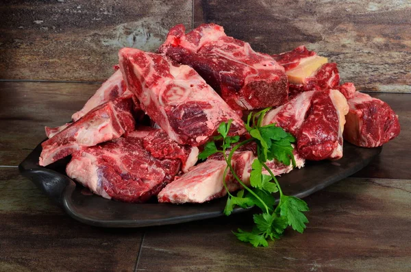 用粘土盘和褐色石头做背景的生肉 用牛肉做背景的生肉 汤用牛肉骨的选择 — 图库照片