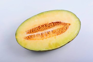 Beyaz arka planda yarı izole edilmiş yuvarlak sarı bir kavun diliminin yakın çekimi. Taze, sulu, yarım karpuz ve çekirdekle kesilmiş. 