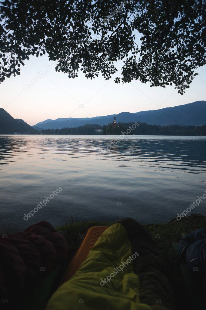 Early morning lake Bled in Slovenia. Calm lake, rising sun behind the mountains, Alps. Sleeping bags in the foreground, Outdoor Adventure in the Triglav National Park.