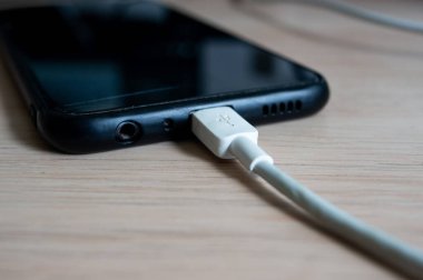 Akıllı telefonu masanın üzerinde şarj ediyor..