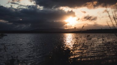 Gün batımı, dağların arkasında bir körfezin yazı tipinde. İskoç sahillerinde güneş batıyor..