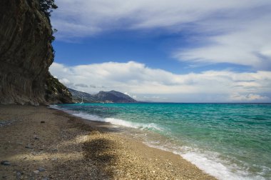 Temiz su ve ünlü kaya oluşumuyla güneşli bir sahil. Cala Luna plajı, Sardinya, İtalya
