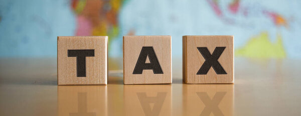 Надпись TAX на деревянных кубиках, изолированных, на фоне политической карты.