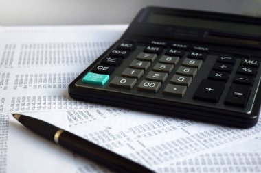 Çalışma alanı olarak bir ofis masasında hesap makinesi ve kalem bulunan iş belgeleri. Bulutla kaplı