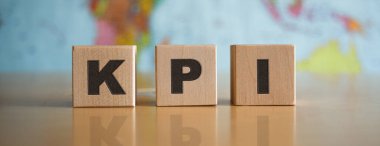 Tahta küplere yazılmış KPI yazısı, izole edilmiş, politik bir haritanın arka planında.