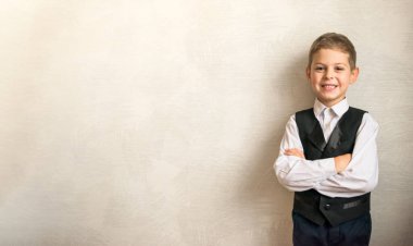 Okul üniformalı mutlu çocuk ilk kez okula gidiyor. Kapalı alanda hafif bir arka planda öğrenci. Harfleriniz için boş arkaplan hazır.