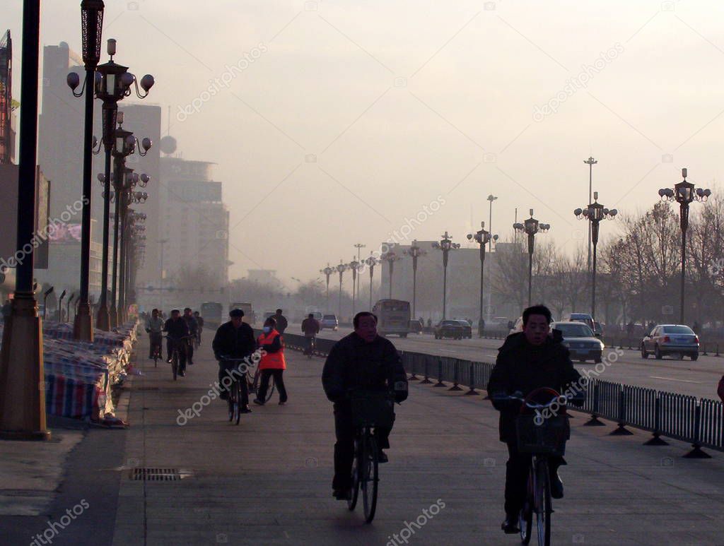 Tangshan, China - January 20, 2005:  Unidentified people riding bikes in early morning smog.  Tangshan, Hebei sheng Province, Northeastern China