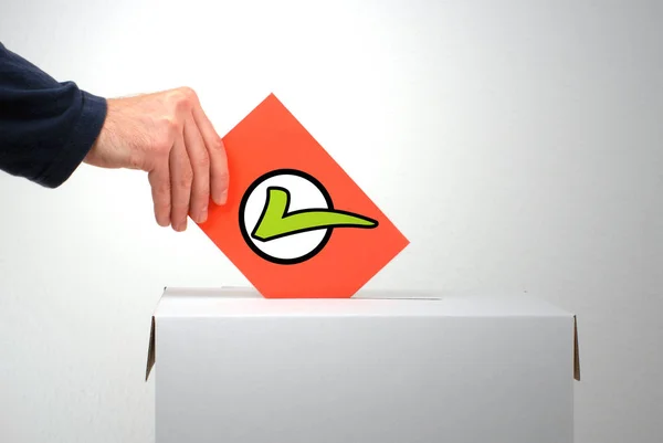 Hand inserting envelope with green tick into ballot box — Stock Photo, Image