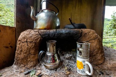 Ahşap bir evde çaydanlık, çaydanlık ve kupalarla yanan odun ocağı. Peru.