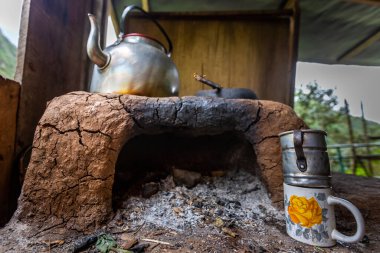 Ahşap bir evde çaydanlık, çaydanlık ve kupalarla yanan odun ocağı. Peru.