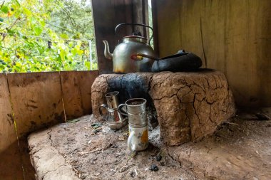 Ahşap bir evde çaydanlık, çaydanlık ve kupalarla yanan odun ocağı. Peru.