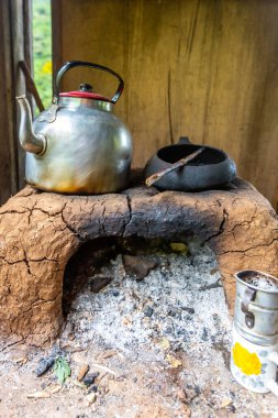 Ahşap bir evde çaydanlık, çaydanlık ve kupalarla yanan odun ocağı. Peru.