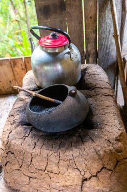 Ahşap bir evde çaydanlık, çaydanlık ve kupalarla yanan odun ocağı. Peru.