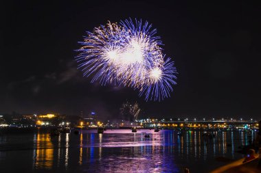 Fireworks gece gökyüzü ve su ayna yansıması zemin üzerine sarı yaprakları ile mavi dikenli ateş topları şeklinde
