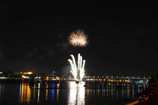 Splashes of fireworks in the form of multi-colored fireballs of fireworks for the day of the city in Kostroma with multi-colored highlights on the Volga river