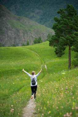 Mutlu genç kadın yeşil bir çayırda özgürlüğün tadını çıkarıyor. Doğada olmanın keyfi. Stres Rahatlama Konsepti. Yaz seyahati hafif. Etkin yaşam biçimi.