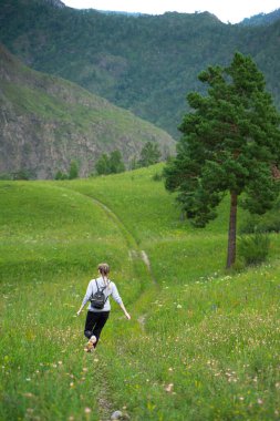 Mutlu genç kadın yeşil bir çayırda özgürlüğün tadını çıkarıyor. Doğada olmanın keyfi. Stres Rahatlama Konsepti. Yaz seyahati hafif. Etkin yaşam biçimi.