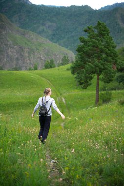 Mutlu genç kadın yeşil bir çayırda özgürlüğün tadını çıkarıyor. Doğada olmanın keyfi. Stres Rahatlama Konsepti. Yaz seyahati hafif. Etkin yaşam biçimi.