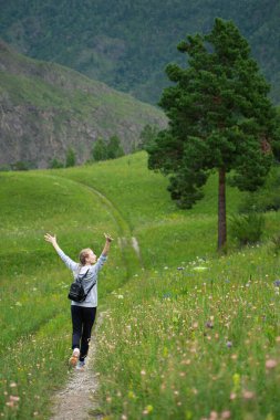 Mutlu genç kadın yeşil bir çayırda özgürlüğün tadını çıkarıyor. Doğada olmanın keyfi. Stres Rahatlama Konsepti. Yaz seyahati hafif. Etkin yaşam biçimi.