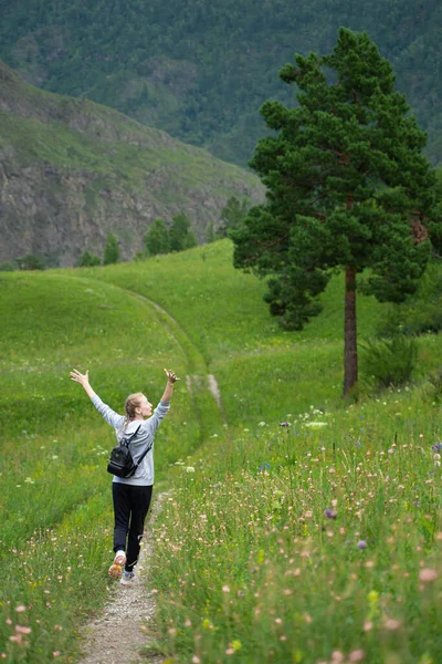 Mutlu genç kadın yeşil bir çayırda özgürlüğün tadını çıkarıyor. Doğada olmanın keyfi. Stres Rahatlama Konsepti. Yaz seyahati hafif. Etkin yaşam biçimi.