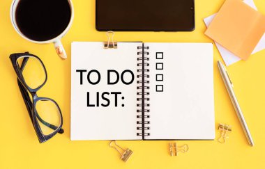 Sarı sehpada, kahve, akıllı telefon, gözlük, kalem ve ataçlarla yapılacaklar listesi şeklinde mesaj atın. Üst görünüm