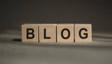 Tahta bir blokta yazan blogdan bir kelime. Tasarımınız ve konseptiniz için ahşap arka planı olan mavi bir masadaki BLOG metni.