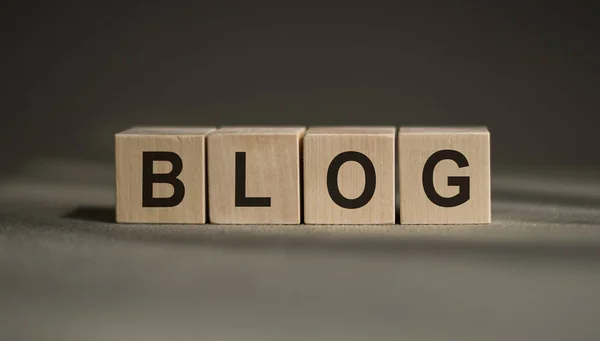 BLOG word written on a wooden block. BLOG text on a blue table with a wooden background for your design, concept.