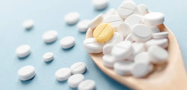 Weiße Tabletten Und Eine Gelbe Tablette Auf Blauem Hintergrund — Stockfoto