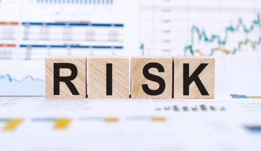 Tahta küplere yazılmış RISK kelimesi. Mali risk değerlendirmesi, risk ödülü ve portföy risk yönetimi konsepti. Finansal grafikler ve grafikler