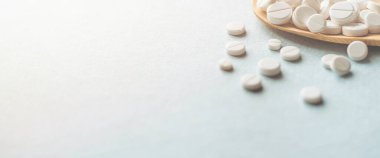 Beyaz haplar, mavi masadaki tahta kaşıkta tabletler. Tıp ve sağlık konsepti. Eczacılık. Haplar ve vitaminler.