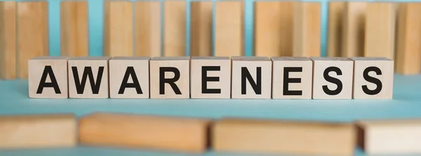 AWARENESS kelime kavramı mavi bir masa ve ahşap arka plan üzerinde ahşap küplere yazılmış