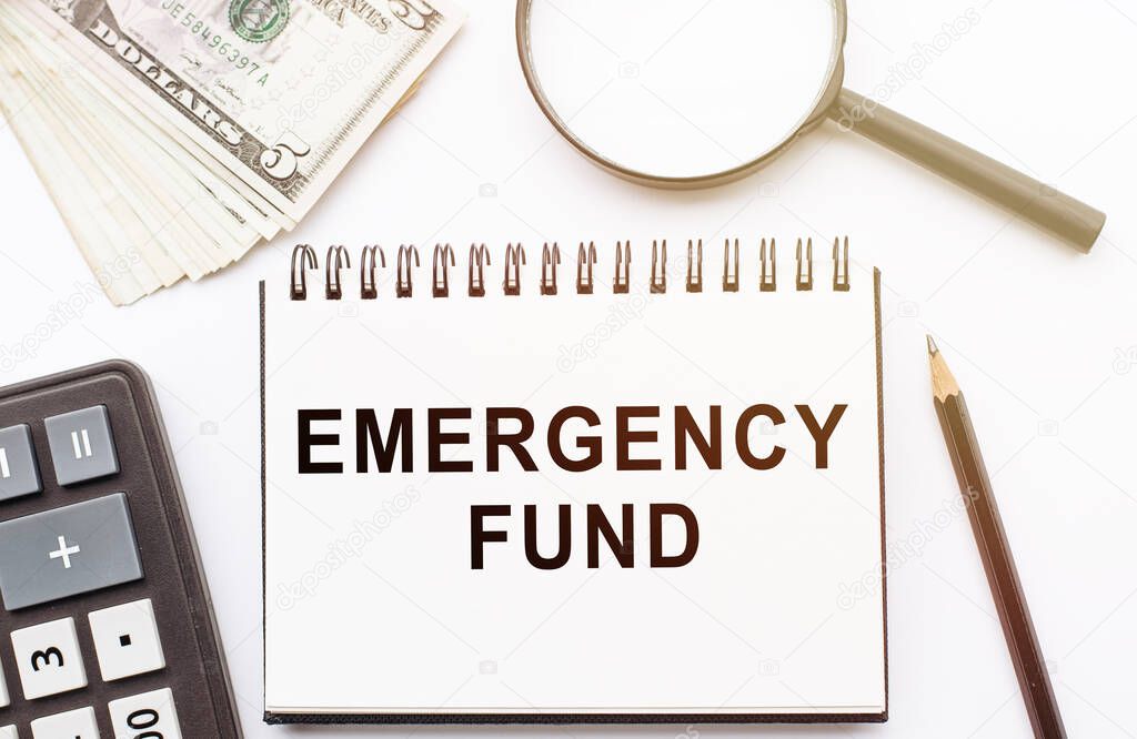 Emergency Fund text written on notebook with calculator, magnifier, dollar bills and pen. Financial concept