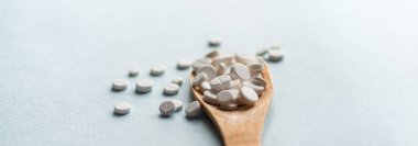 Beyaz haplar, mavi masadaki tahta kaşıkta tabletler. Tıp ve sağlık konsepti. Eczacılık. Haplar ve vitaminler.
