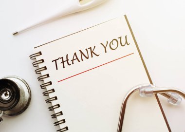 Teşekkürler. Tıbbi steteskop ve termometreyle beyaz arkaplan üzerine yazı. Bir salgın sırasında sağlık çalışanlarına minnettarlık kavramı